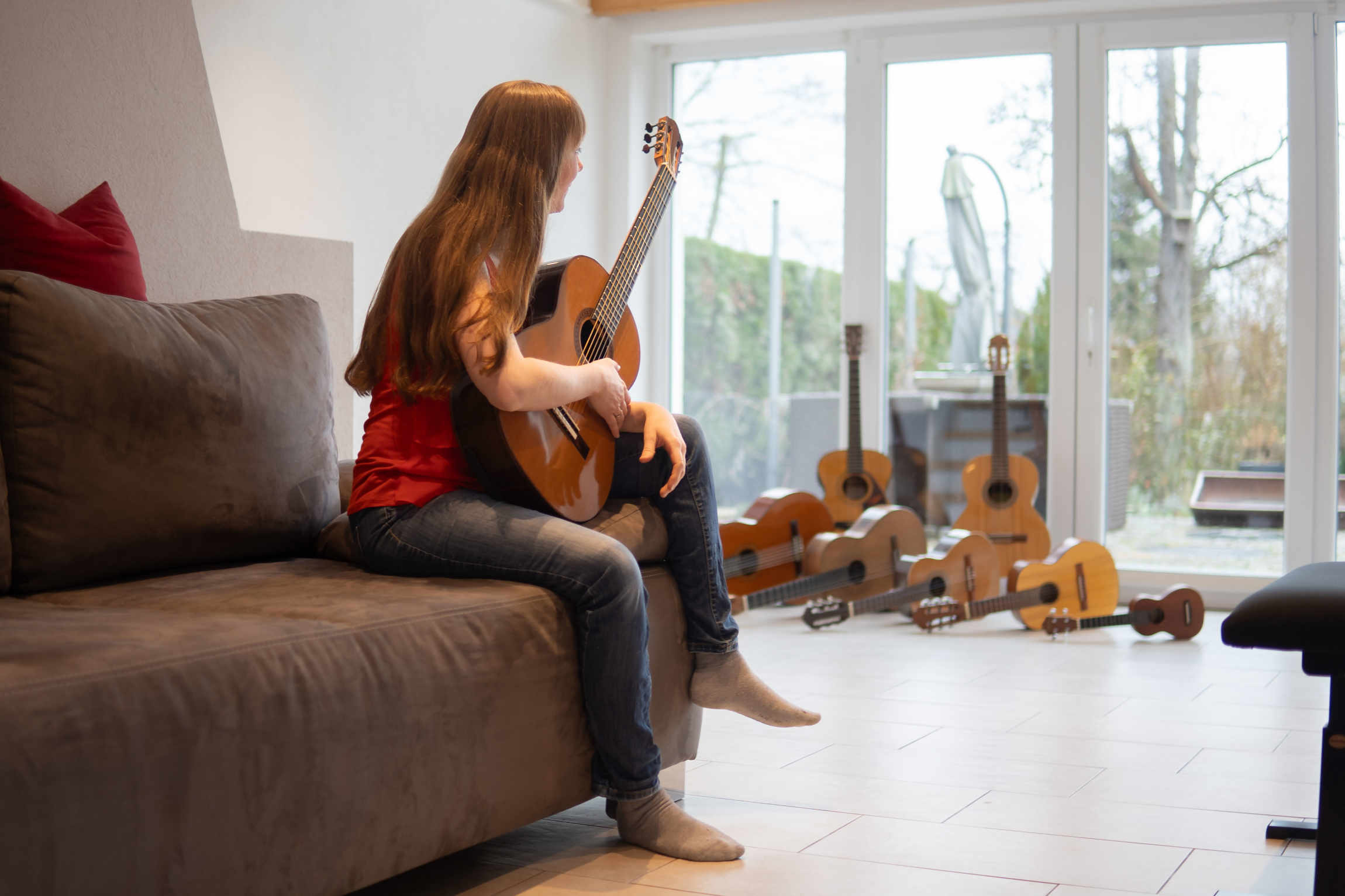 Claudia Kluck sitzt mit einer Gitarre auf dem Sofa