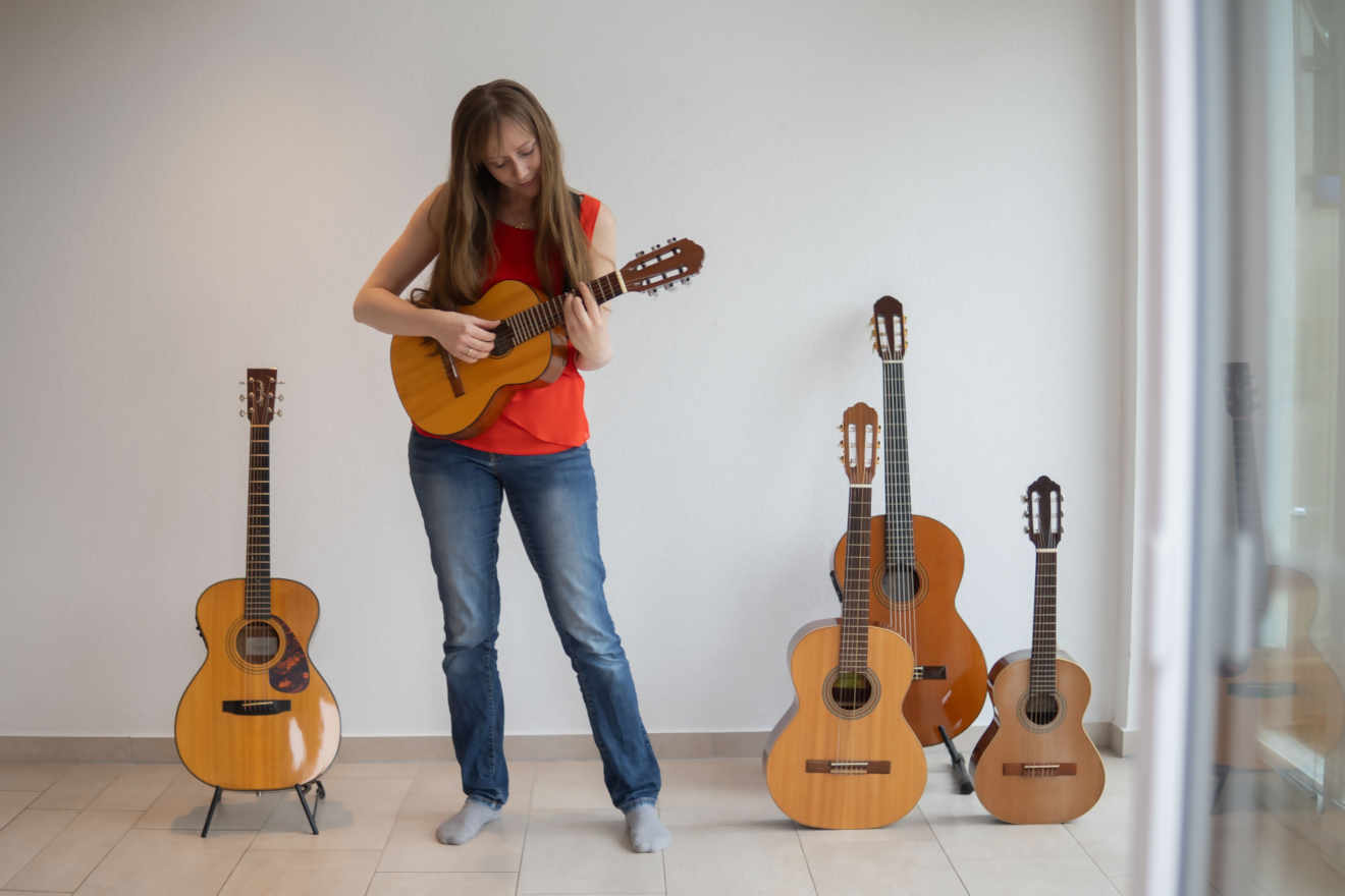 Claudia Kluck spielt Gitarre, neben ihr stehen weitere Gitarren