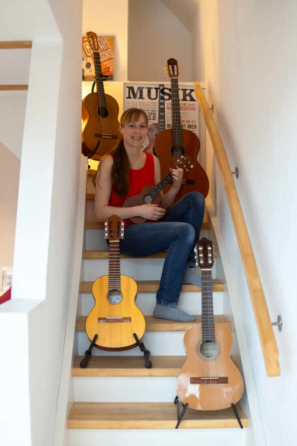 Claudia Kluck hockt mit Gitarren auf einer Treppe