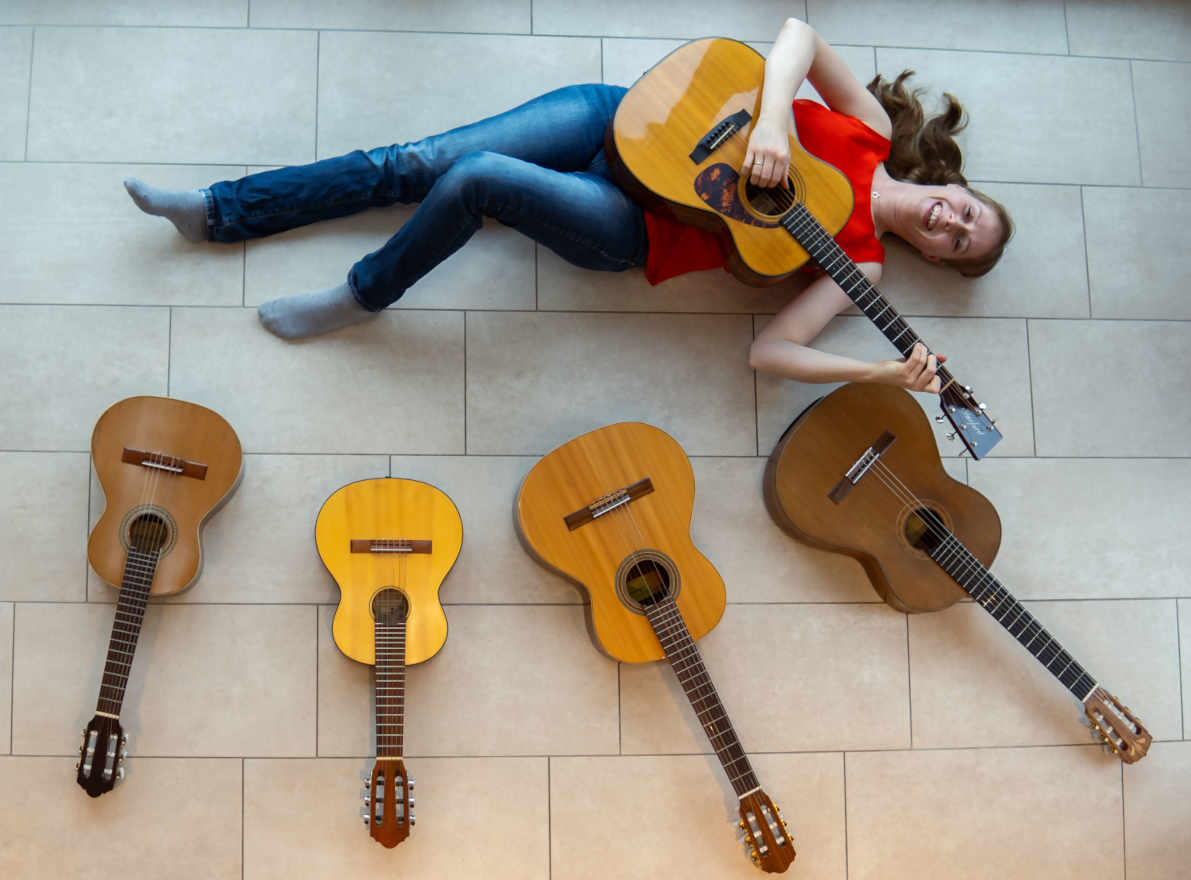 Claudia Kluck liegt samt mehrerer Gitarren auf dem Boden