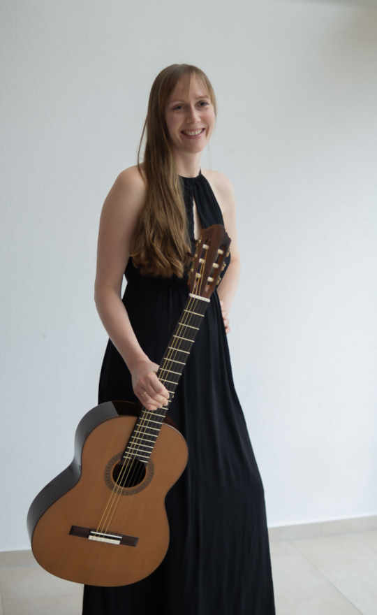 Claudia Kluck mit Gitarre im Konzert-Outfit betritt die Bühne